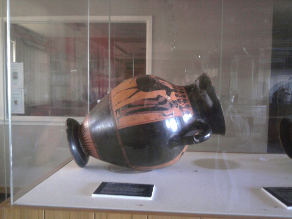 Amphora fallen on its side in exhibition case.