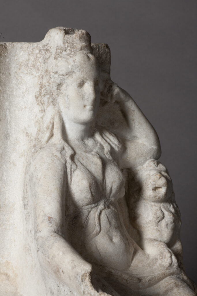White marble statue of a seated goddess with a lion at her side. This is the goddess Cybele.