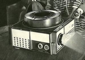 Black and white vintage advert showing a slide projector in use.