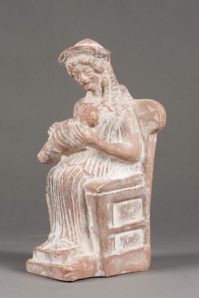 Plaster cast copy of a figurine of a seated woman holding a baby.